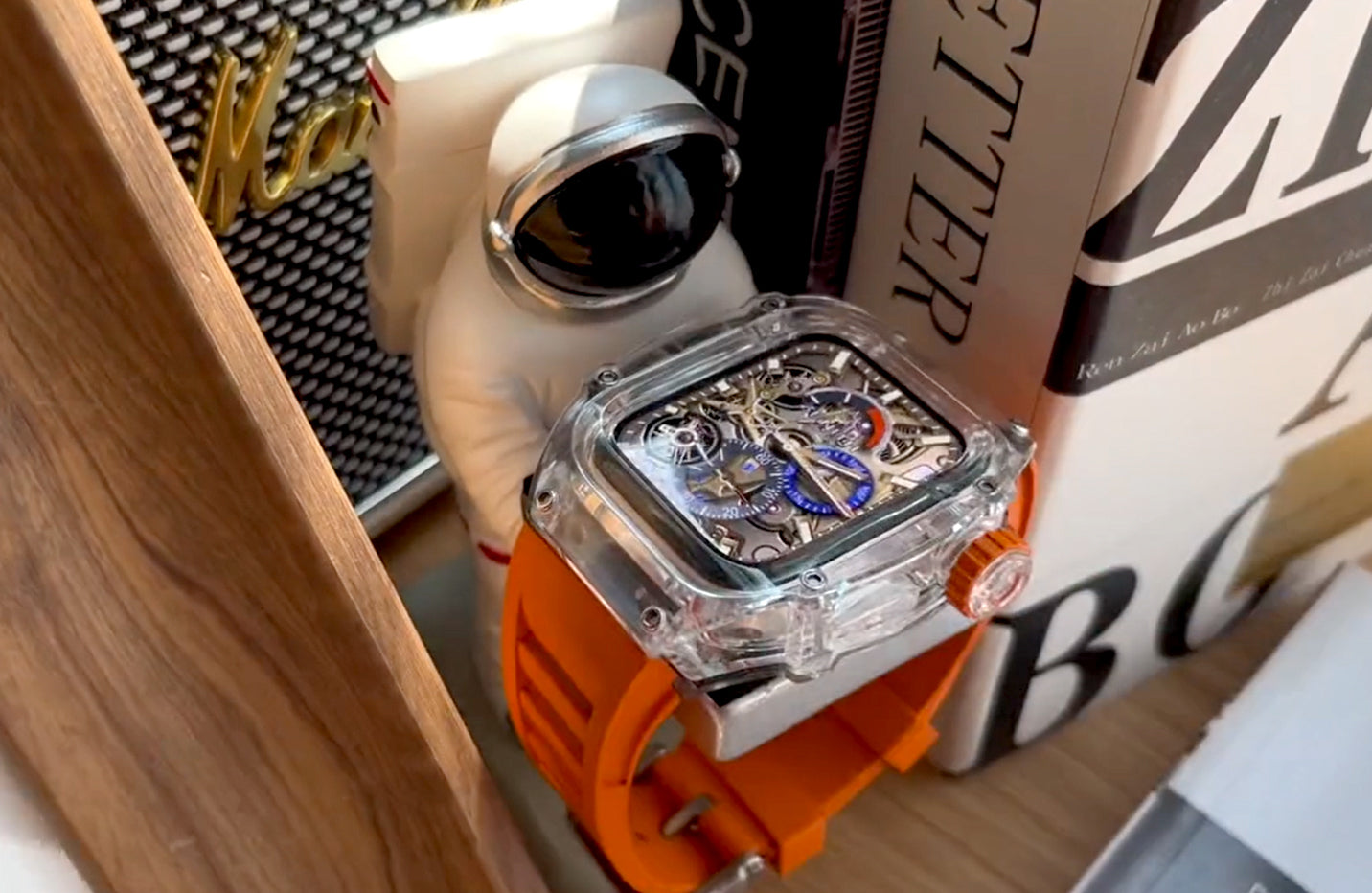 An Astronaut holding an Apple Watch which applied Kewsuma Ice Cube Transparent Apple Watch Case with Fluorescent Orange watch strap